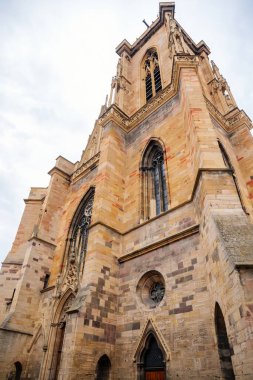 Colmar, Alsace, France, 4 July 2022: town capital of Alsatian wine, narrow picturesque street with medieval colorful houses, Roman Catholic Gothic St Martins Church with tower at summer day