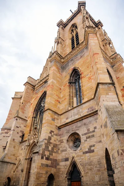 Colmar, Alsace, France, 4 July 2022: town capital of Alsatian wine, narrow picturesque street with medieval colorful houses, Roman Catholic Gothic St Martins Church with tower at summer day