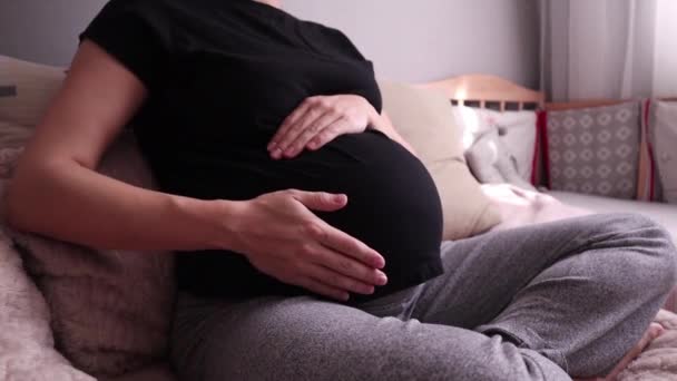 Zwangere vrouw zitten en strelen haar buik — Stockvideo