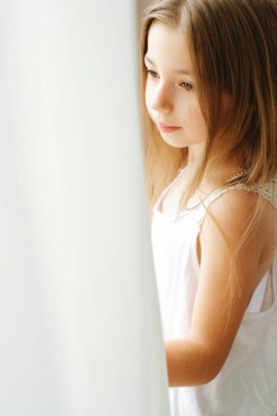 Sabahları pencerenin yanında sarı saçlı sekiz yaşında bir kız çocuğunun portresi.