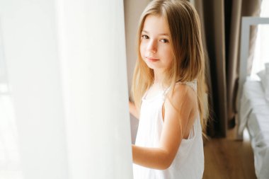 Sabahları pencerenin yanında sarı saçlı sekiz yaşında bir kız çocuğunun portresi.