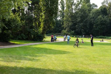 Evere, Brüksel Başkent Bölgesi, Belçika - 20 09 2021: Kentin yeşil alanlarında oynayan küçük çocuklu aileler