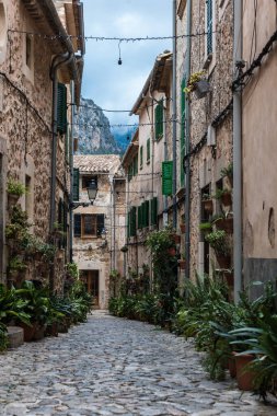 Valldemossa, Mallorca / İspanya - 12 26 2017: Çiçekler ve bitkilerle süslenmiş eski kentin sokaklarında yürüyen turistler