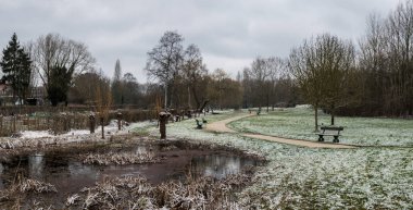 Terk edilmiş şehir parkı kış sabahının erken saatlerinde taze kar tabakasıyla kaplı.