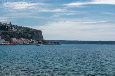 Piran, Slovenya - 04 07 2018: Mavi deniz, körfez ve arkaplanda kayalıklar olan limana bakın
