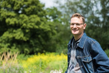 Yazın Brüksel, Belçika 'da yeşil bir geçmişi olan, mavi kotlu 40 yaşındaki bir adamın portresi.