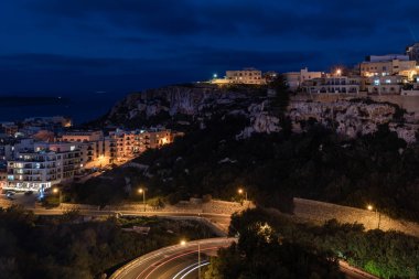 Akdeniz, evler ve kaya yapılarıyla Malta 'daki Mellieha körfezi üzerinde gece görüşü