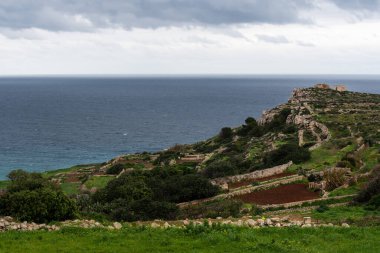 Selmun, Malta 'da kayalıklı yeşil bir manzaraya ve arka planda Akdeniz manzarasına bakın.