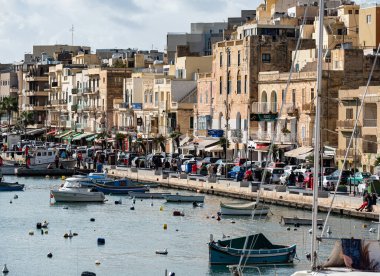 MArsakala, Malta - 01 07 2022: Renkli tekneleri ve tarihi sarı binaları olan liman