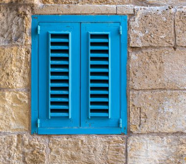Valletta, Malta - 01 07 2022: Mavi kapalı bir pencerenin ayrıntıları sarı tuğlalı bir duvarın