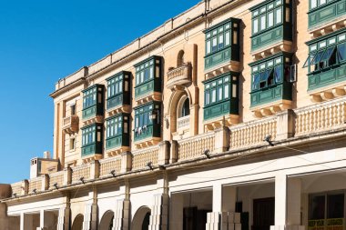Valletta, Malta - 01 07 2022: Sarı cepheli ve yeşil pencereli tarihi evler