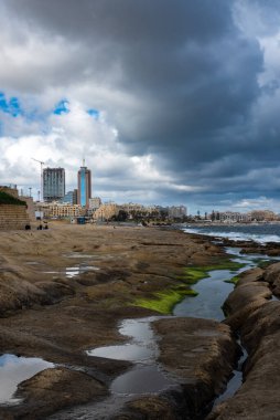 Saint Julian, Malta - 01 07 2022: Sahilin alçak açısı ve arka planda kara bulutlu daireler
