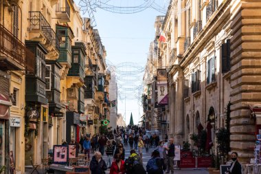 Valletta, Malta - 01 07 2022: İnsanlar ana caddede dükkanlar ve restoranlarla yürüyor