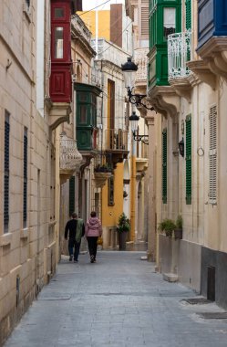 Rabat, Malta - 01 07 2022: Dar sokak ve ahşap kapılı ve pencereli konut evleri cepheleri