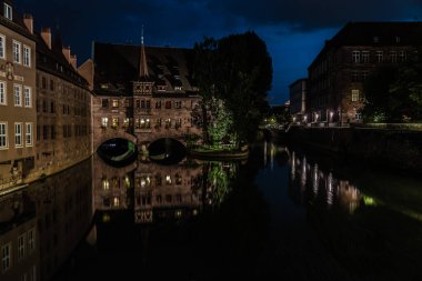 Neurenberg, Bavyera - Almanya - 07 26 2018: Eski kenti gören turistler, geceleyin suya yansıdı