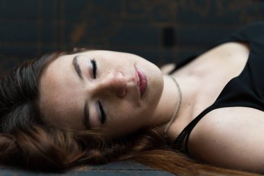 18 yaşında, kızıl saçlı, kanepede uzanmış, gözleri kapalı bir kızın moda portresi.