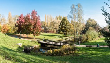 Jette, Brüksel / Belçika - 11 07 2018: Güneşli bir sonbahar gününde Kral Baudouin şehir parkında renkli ağaçlarla oturan insanlar