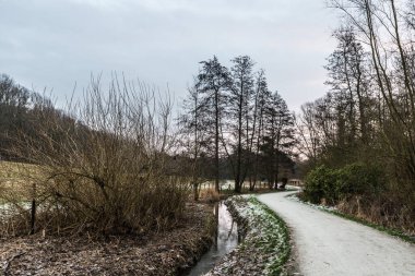 Baudouin Parkı 'nın üzerinde Molenbeek deresi boyunca yürüyen bir patika ve kışın çıplak ağaçlar var.