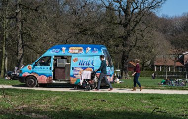 Ixelles, Brüksel / Belçika - 03: 30 2019: Güneşli bir bahar günü Bois de La Cambre şehir parkındaki bir dondurma satıcısına yürüyen genç aile