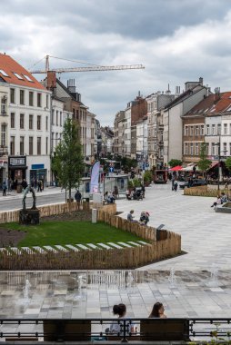 Ixelles, Brüksel - Belçika - 05 31 2019 - Fernand Cocq Meydanı 'ndaki belediye binasının önündeki çeşmede oynayan genç çocuk ve anne