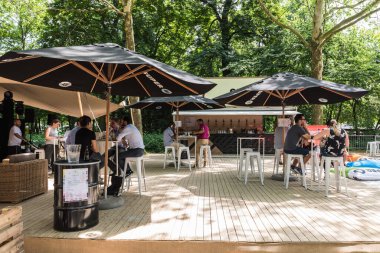 Brüksel Eski Kenti - Belçika - 06: 25 2019 İnsanlar sıcak bir yaz gününde Parc de Bruxelles - Warandepark 'ta güneşli bir barda içki içiyorlar.