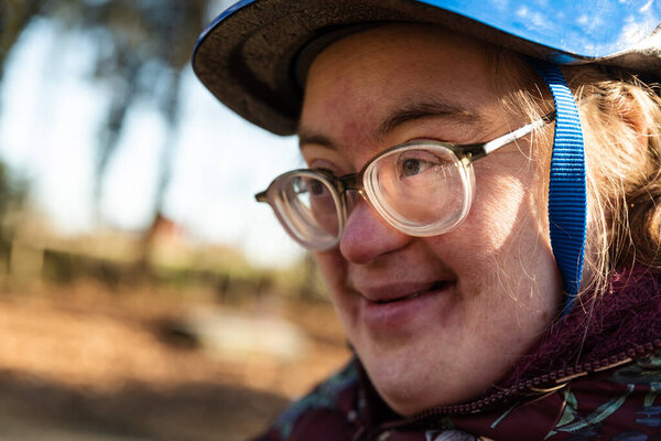 Внешний портрет 39-летней белой женщины с синдромом Дауна, улыбающейся и в велосипедном шлеме