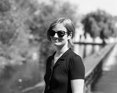 30 yaşında, güneş gözlüklü ve siyah elbiseli çekici bir kadın yaz boyunca botanik bahçesinde poz veriyor, Uppsala, İsveç