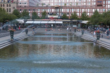 Stockholm, İsveç - 07: 24 2019 Kings bahçesi Kungstradgarden 'da çeşmenin etrafında insanlar oturuyor.