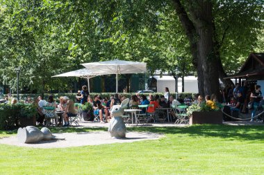 Stockholm, İsveç - 07: 24 2019 Kings bahçesi Kungstradgarden 'da insanlar ağaçların ve çimenlerin etrafında oturuyor.