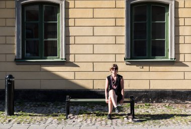 İsveç 'te tipik bir neo klasik evin önünde oturan gülümseyen 30 yaşındaki beyaz bir kadının portresi.