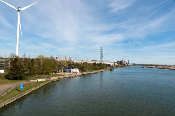 Genk, Limburg, Belçika - 04 12 2022 - Endüstriyel faaliyet ve Albert Kanalı 'nın kıyısında bir yel değirmeni fabrikası