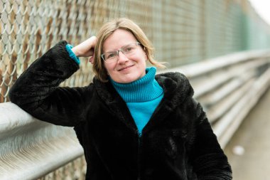 Endüstriyel çitlere karşı poz veren, siyah kürklü bir kadın portresi, Anderlecht, Belçika