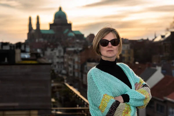 Arka planda günbatımında Brüksel silueti ile çatıda poz veren 30 yaşında çekici beyaz bir kadının portresi, Belçika