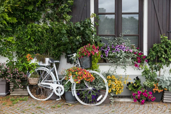 Jette, Brüksel Başkent Bölgesi Belçika - 07 05: 2020: Çiçeklerle süslenmiş eski bir kır evinde duran antika bisiklet