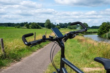 Breda, North Brabant, The Netherlands, 08 09 2022 -   Steer of a trekking bike with the green surroundings of the River Mark in the background