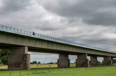 Tiel, Gelderland, The Netherlands, 07 14 2022 - Concrete suspension bridge of the A15 highway surrounded by green meadows