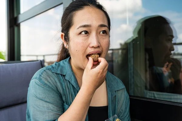 Portrait of a 32 year old Japanese woman eating chocolate, Brussels
