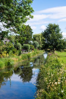 Creek around the village of Zwolle, Gelderland, the Netherlands with green trees reflecting against blue sky