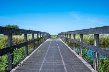 Onlanden, Drenthe, The Netherlands, 07 20 2022 - Wooden walking and biking trail over blue sky at the Dutch countryside