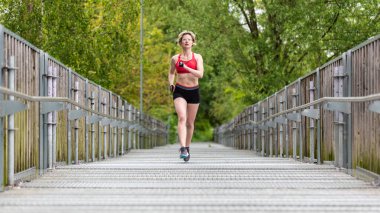 30 yaşında şortlu ve spor sutyenli çekici bir kadın, Belçika.