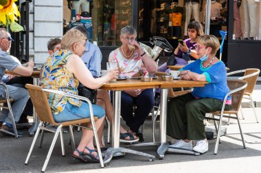 Leuven, Flaman Brabant - Belçika - 06 20 2021 Olgun bayan arkadaşlar güneşli bir terasta içiyorlar