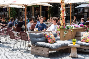 Leuven, Flaman Brabant - Belçika - 06 20 2021 Güneşli bir terasta oturan genç öğrenci arkadaşlar
