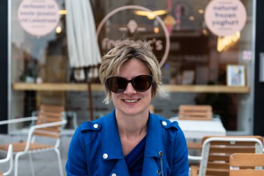 Çekici 30 yaşında bir kadın güneşli bir terasta bir fincan kahve içiyor.