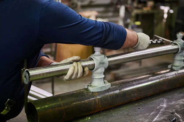 Tubo de metal nas mãos de um trabalhador na oficina para a fabricação de postes de lâmpada. Processo de montagem do produto — Fotografia de Stock