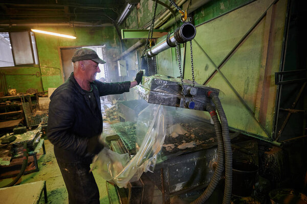 The process of molding and firing of industrial ceramic products in the workshop of the plant. Elderly man - worker controls