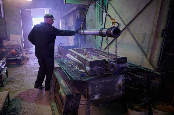 The process of molding and firing of industrial ceramic products in the workshop of the plant. Elderly man - worker controls