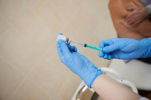 Een verpleegkundige injecteert het Covid-19 coronavirus vaccin in een oudere patiënt met een injectiespuit intramusculair in de schouder. — Stockfoto