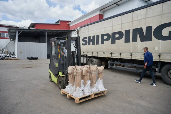 A loader transports pipes to a container ship in the yard of the plant near the warehouse — Stock Photo, Image