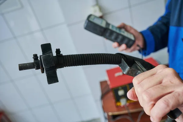 Otomobil tamircisinin elinde bulunan bir arabanın egzoz gazlarını kontrol etmek için giriş cihazı