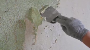 Duvardan eski duvar kağıtlarını spatula ve doğaçlama araçlarla kazımak, kendi başına bir apartman dairesini onarmak.